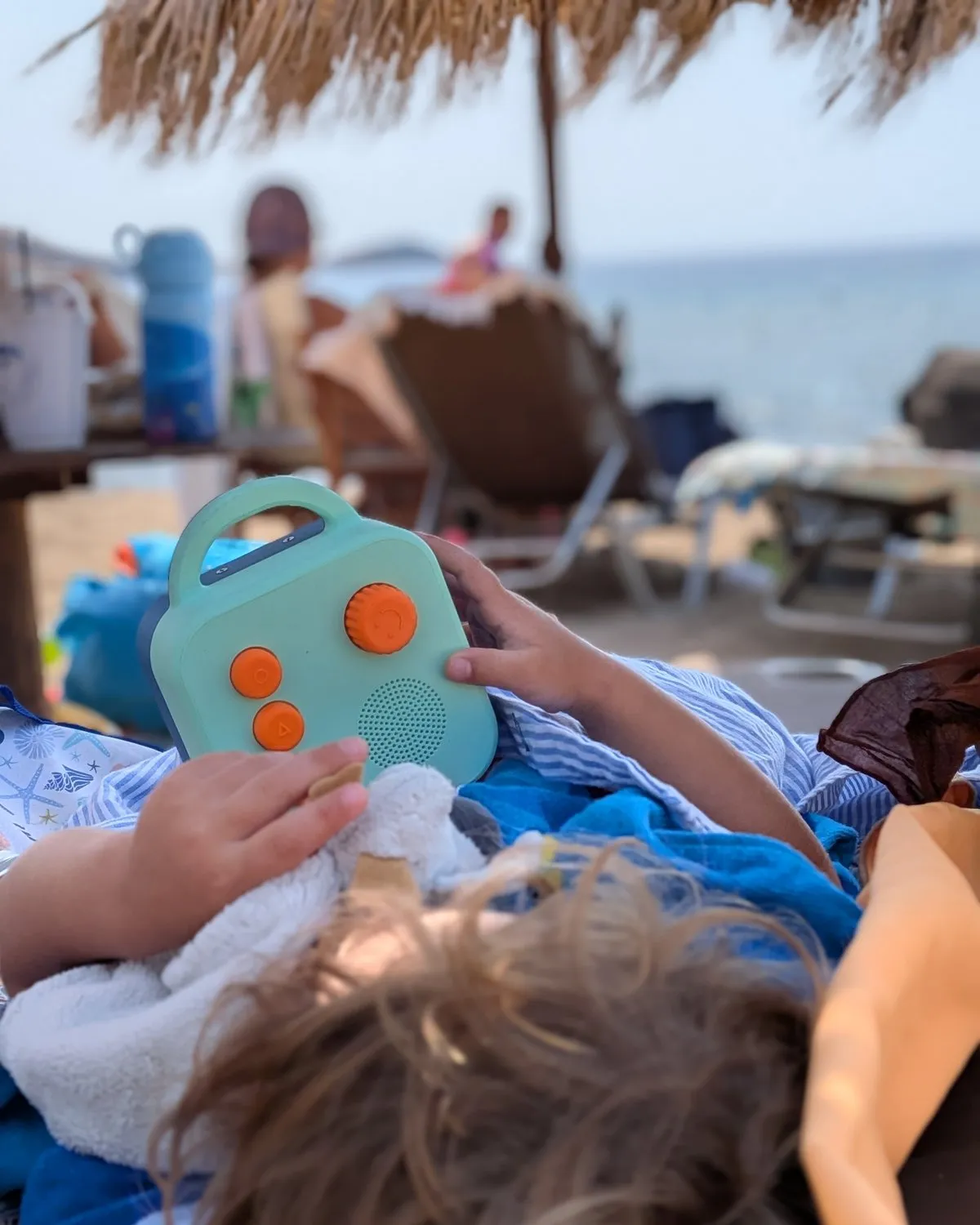 A child on a beach lounger, holding a Koobiba